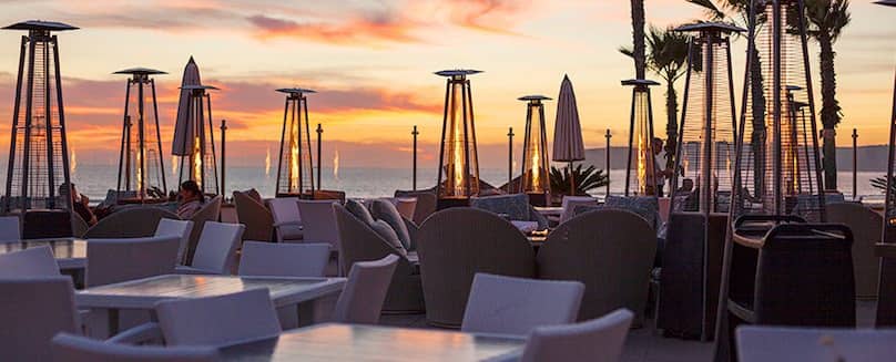 Flüssiggas in Flaschen für die Gastronomie - TEGA Viele-Heizstrahler-und-Stuehle-und-Tische-mit-Ausblick-zum-Meer-bei-Sonnenuntergang
